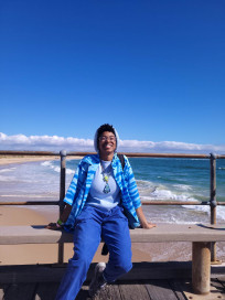 Enali smiling on a pier over an Australian coastline.