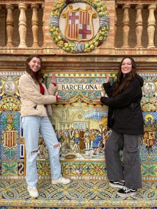 Cassidy and friend posing in front of tile siding to old building. In the siding is the word "BARCELONA"