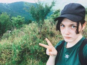 Valeria Sokolova selfie holding up peace sign in front of greenery