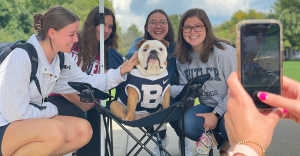 Butler Blue, Butler's Bulldog Mascot, sits on lawn chair with smiling students posing for a photo